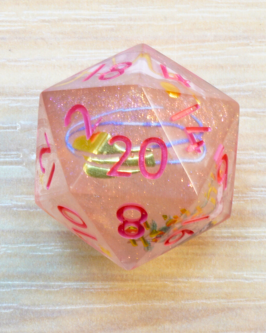 Pink polyhedral die with colorful numbers on a light wooden surface