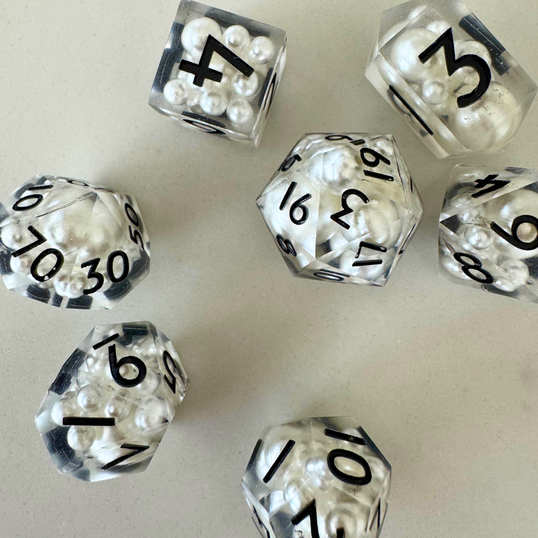 Clear dice with black numbers and white beads on a light gray background