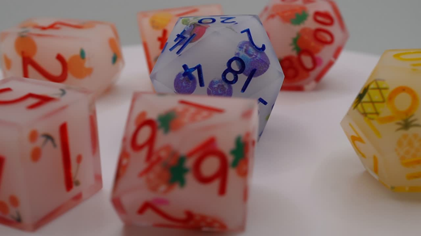 Colorful fruity dice with various numbers and designs on a white surface