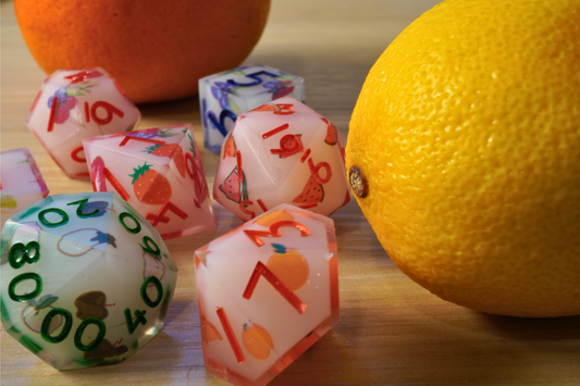 Colorful dice with fruit designs on a wooden surface with oranges.