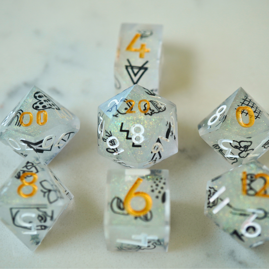 Set of clear dice with black and gold numbers on a marble surface
